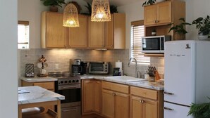 Eine moderne Küche mit Holzschränken, einem weißen Kühlschrank, einer Mikrowelle, einem Toaster und einem Spülbecken.