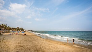 A beach with umbrellas, palm trees, and a clear sky. - Cataleya Villa Chania (Chania)