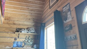A wooden ceiling with horizontal beams, a complaint department sign, and a window with a view. - Cozy Quiet Alaskan Cabin (Soldotna)