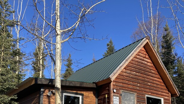 A wooden cabin with two windows, a door, and a porch with red chairs. - Cozy Quiet Alaskan Cabin (Soldotna)