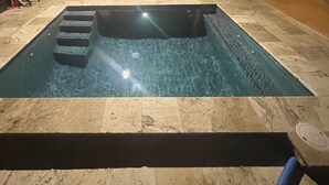 Una piscina rectangular con borde de piedra y escalones de acceso.