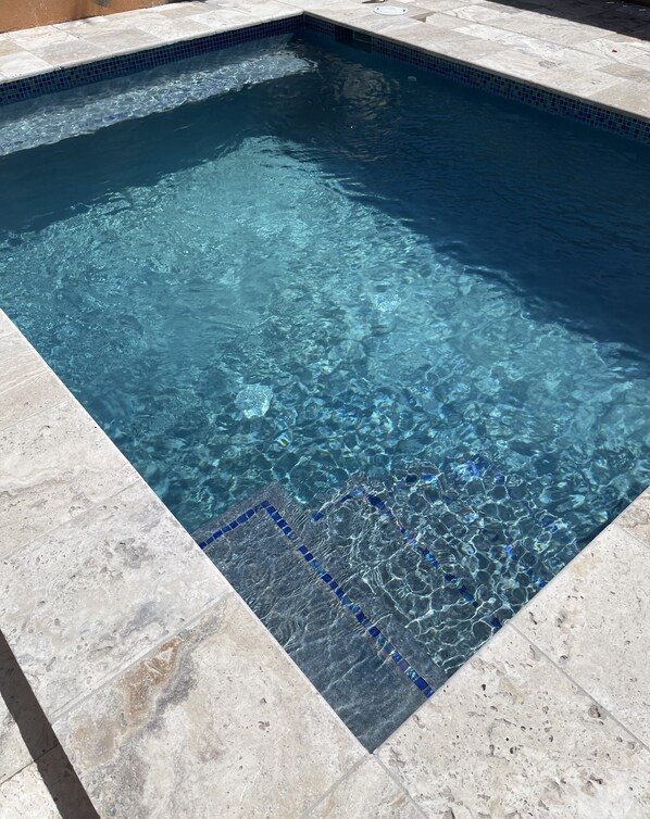 Une piscine rectangulaire à l’eau d’un bleu limpide, dont les bords sont recouverts de carreaux.