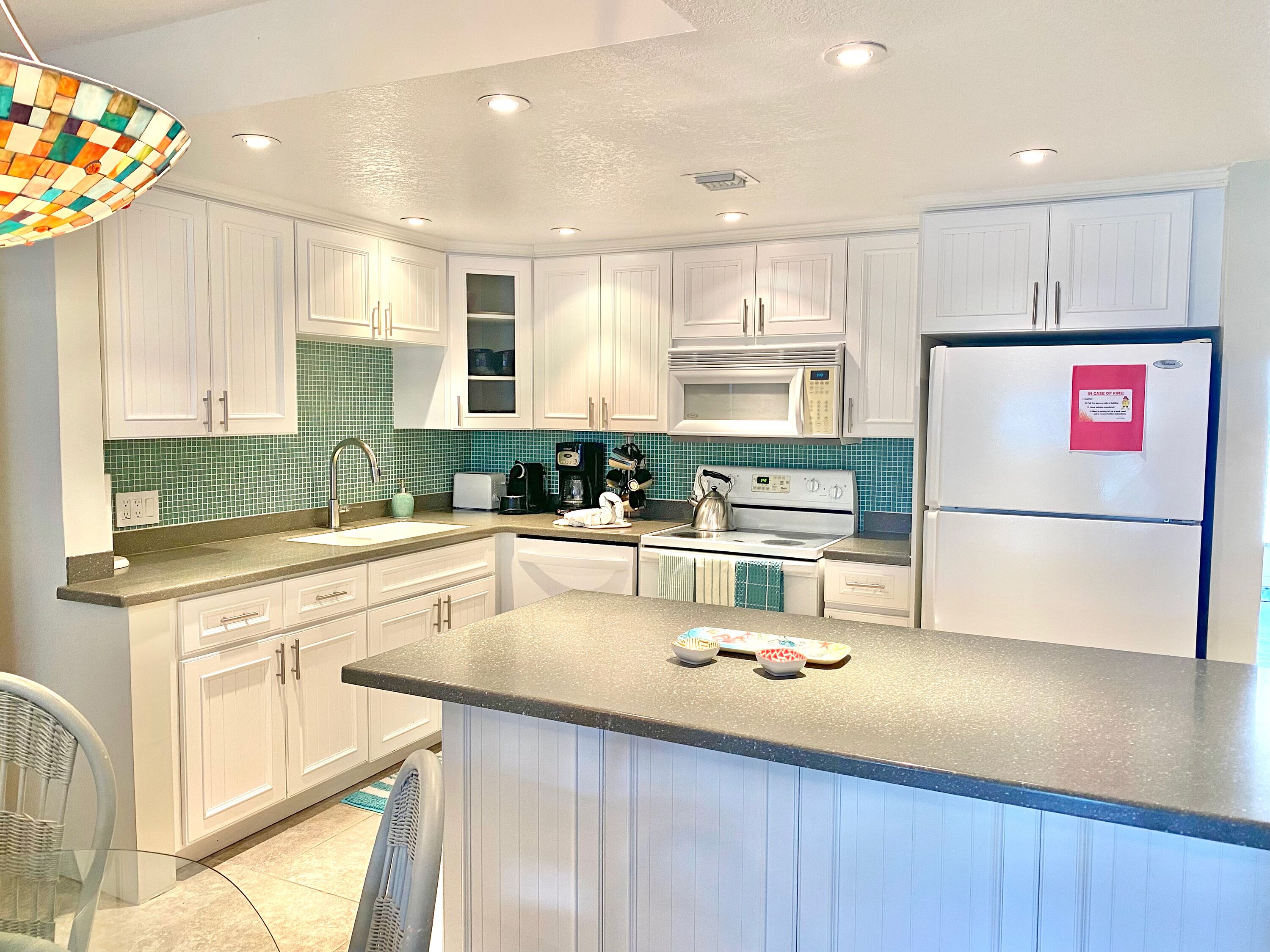A modern kitchen with white cabinets, a stainless steel range, a microwave, and a refrigerator.