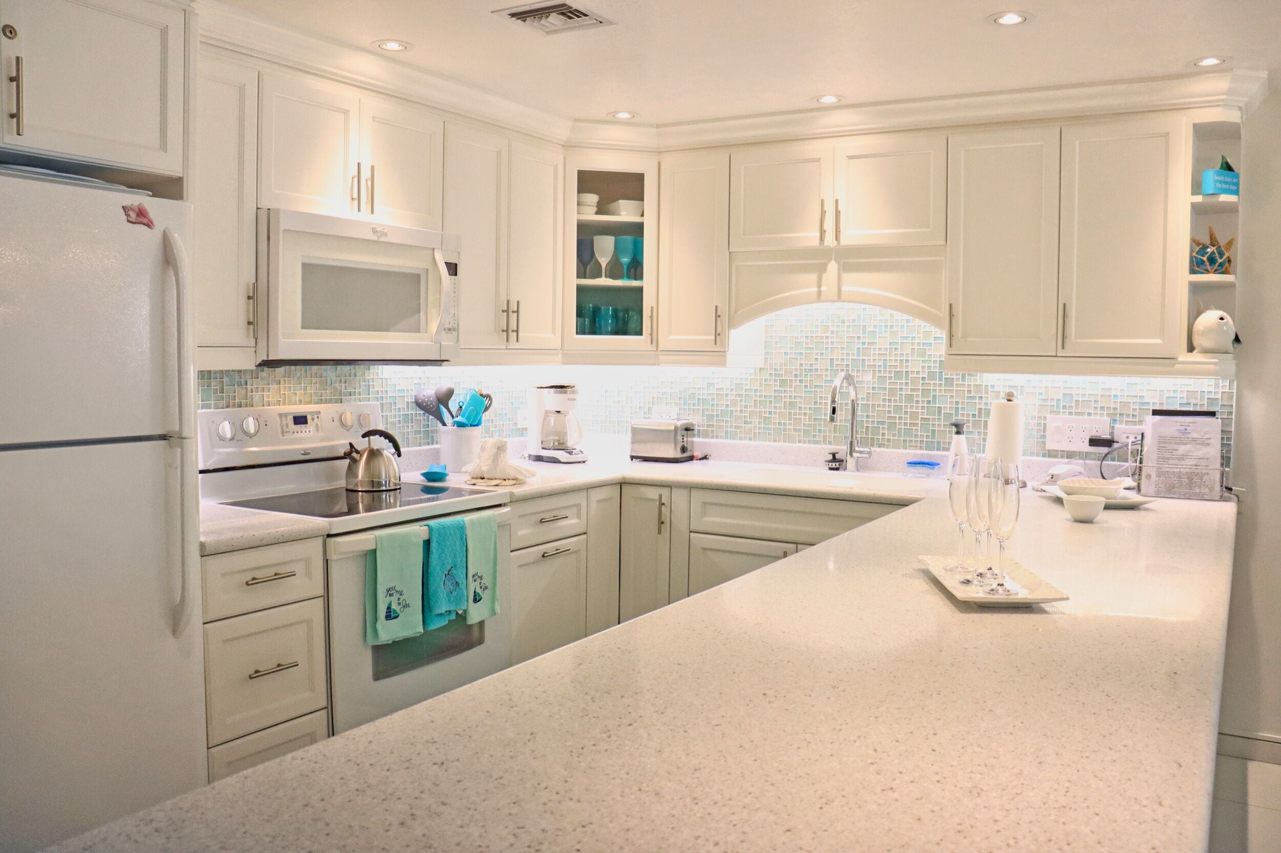 Una cocina moderna con armarios blancos, una isla grande y un salpicadero de azulejos.