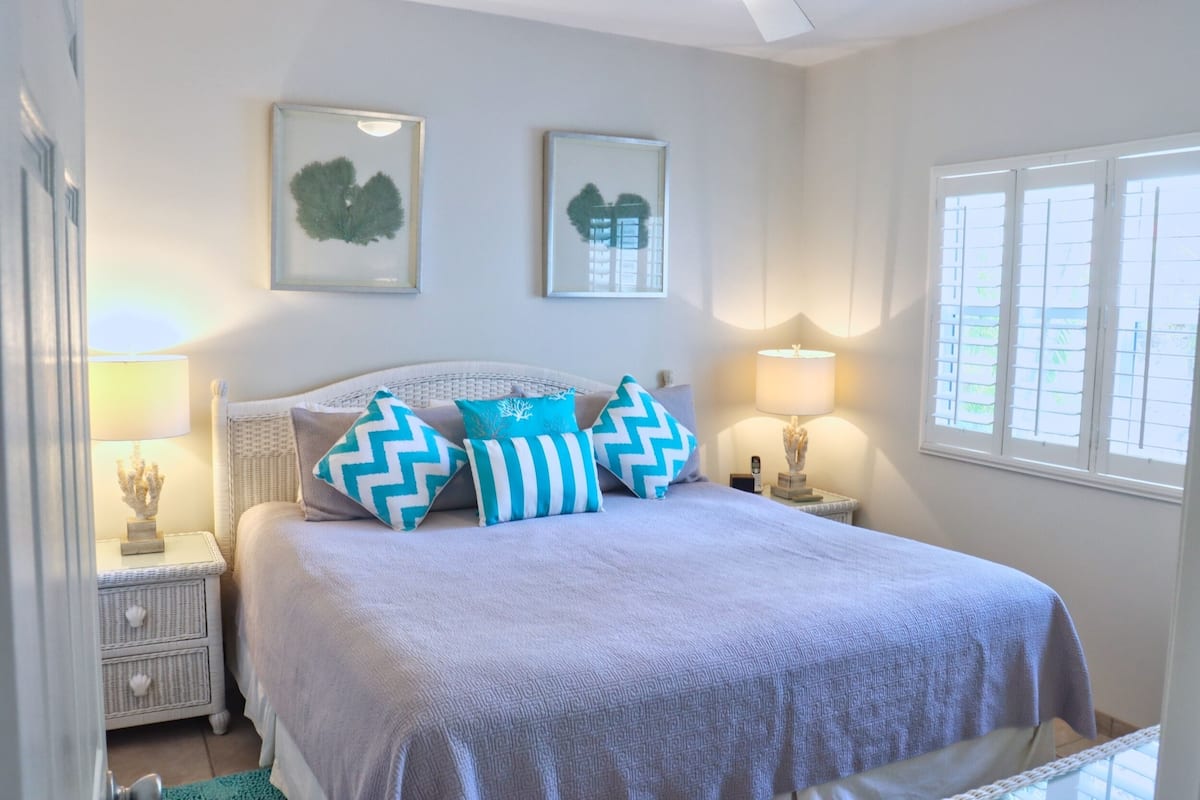 A neatly arranged bedroom with a bed, two bedside tables, and wall-mounted artwork.