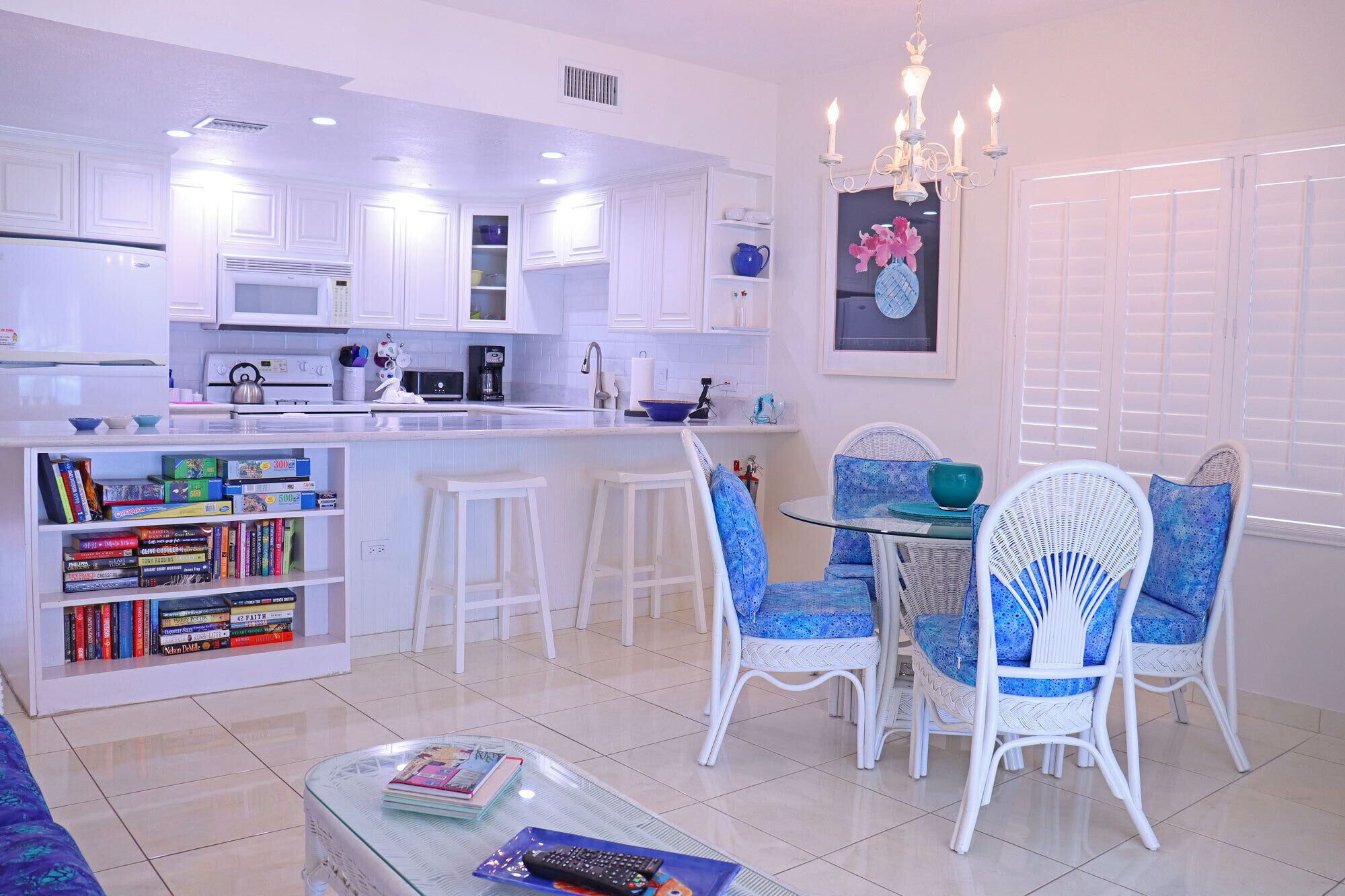 A modern kitchen with white cabinets, a central island, and a dining area with blue chairs.