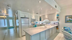 A modern kitchen with white cabinetry, a large island, and a view of the ocean.