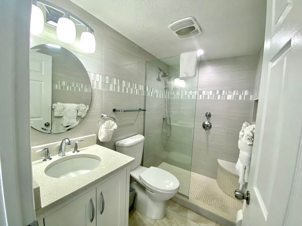 A modern bathroom with a sink, toilet, and glass-enclosed shower.