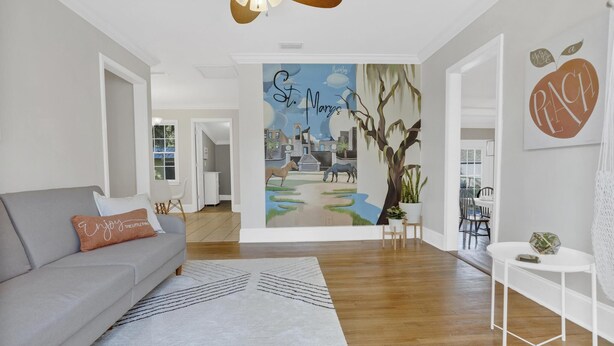Un salon moderne avec un canapé gris, un tapis à motifs et une fresque murale représentant un paysage urbain.