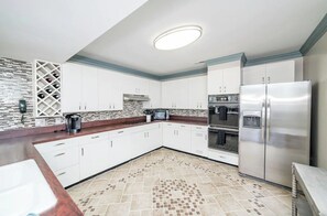Enjoy cooking in this well-equipped kitchen with oven, stainless steel refrigerator, and sleek cabinetry.