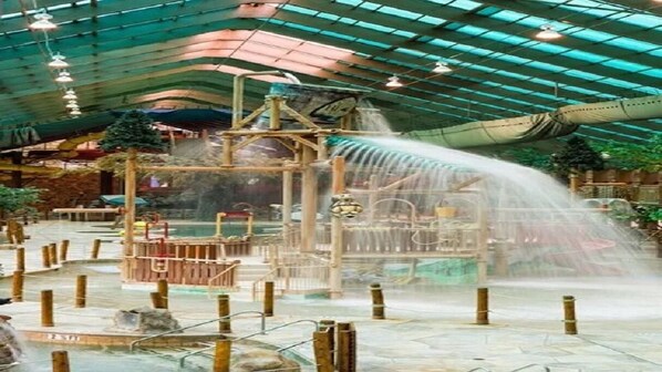 Explore the central water feature surrounded by play structures and platforms under a high ceiling with a translucent roof.