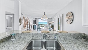 A modern kitchen with a double sink, granite countertops, and a view to the outside.