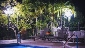 A poolside area with a pool, lounge chairs, and a table. - House on water canal, 5 minutes from downtown and beach. (Naples)