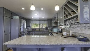 Eine moderne Küche mit Granit-Arbeitsplatten, Edelstahlgeräten und einem Weinkühlschrank.