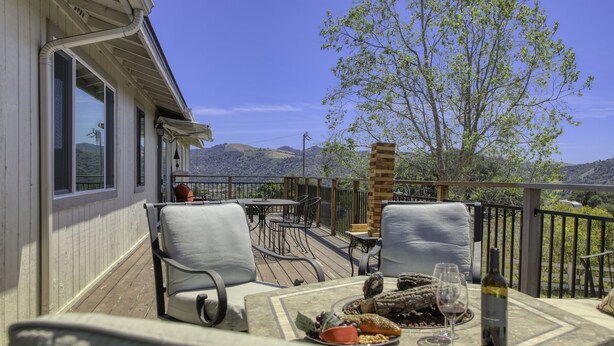 Eine Terrasse mit Sitzgelegenheit, einem Tisch mit Speisen und Getränken sowie Blick auf die Landschaft.