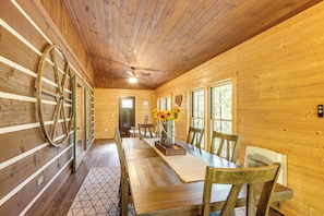 Un interior de madera con una mesa de comedor, sillas y una gran rueda de madera.