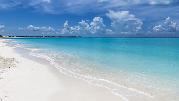 Una playa con agua turquesa cristalina y arena blanca.