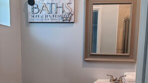 Un baño con inodoro, lavamanos y un cartel decorativo en la pared.