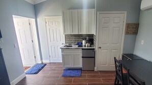 Una cocina compacta con armarios blancos, horno integrado y pileta de acero inoxidable.
