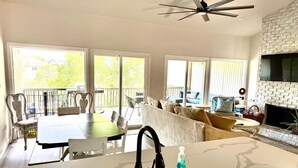 A spacious living area with a fireplace, a dining table, and a kitchen with a sink. - Lake Travis townhome-Pool-Marina-Boat ramp-Golf (Point Venture)
