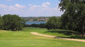 A golf course with a clear view of a lake and distant buildings. - Lake Travis townhome-Pool-Marina-Boat ramp-Golf (Point Venture)