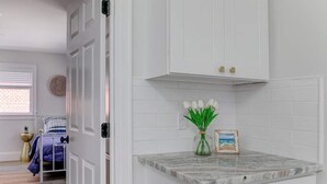 A kitchen with white cabinets, a marble countertop, and a vase with flowers.