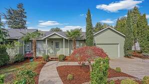 A two-story house with a front porch, a garage, and a well-maintained garden with mulch and shrubs. - Happy Valley Home, Game Room, & 8 beds! (Happy Valley)