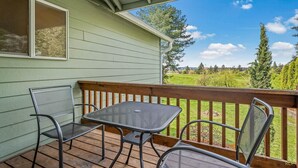 A covered outdoor area with a table and chairs, overlooking a green landscape. - Happy Valley Home, Game Room, & 8 beds! (Happy Valley)