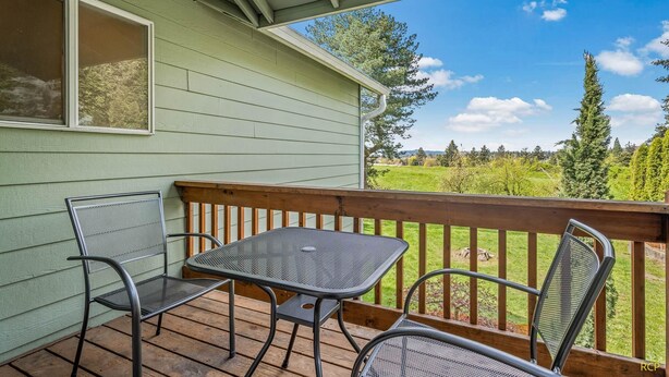 A covered outdoor area with a table and chairs, overlooking a green landscape. - Happy Valley Home, Game Room, & 8 beds! (Happy Valley)