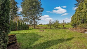 A well-maintained grassy area with a stone bench, surrounded by various trees and shrubs. - Happy Valley Home, Game Room, & 8 beds! (Happy Valley)