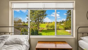 A bedroom with a large window, two beds, and a small wooden table. - Happy Valley Home, Game Room, & 8 beds! (Happy Valley)