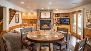 Una sala acogedora con chimenea, un revestimiento de piedra, armarios de madera, un televisor y una mesa de comedor con sillas.