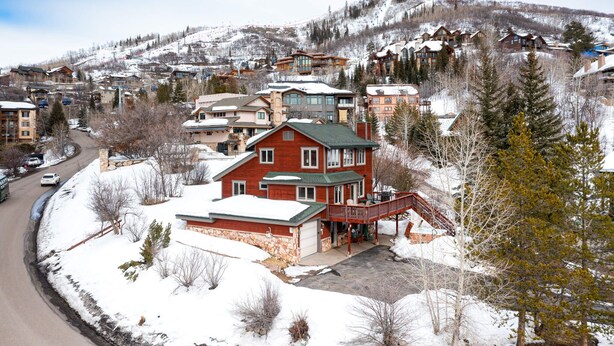 Un edificio grande de varios pisos con fachada roja y techo verde, rodeado de árboles cubiertos de nieve y un paisaje montañoso al fondo.
