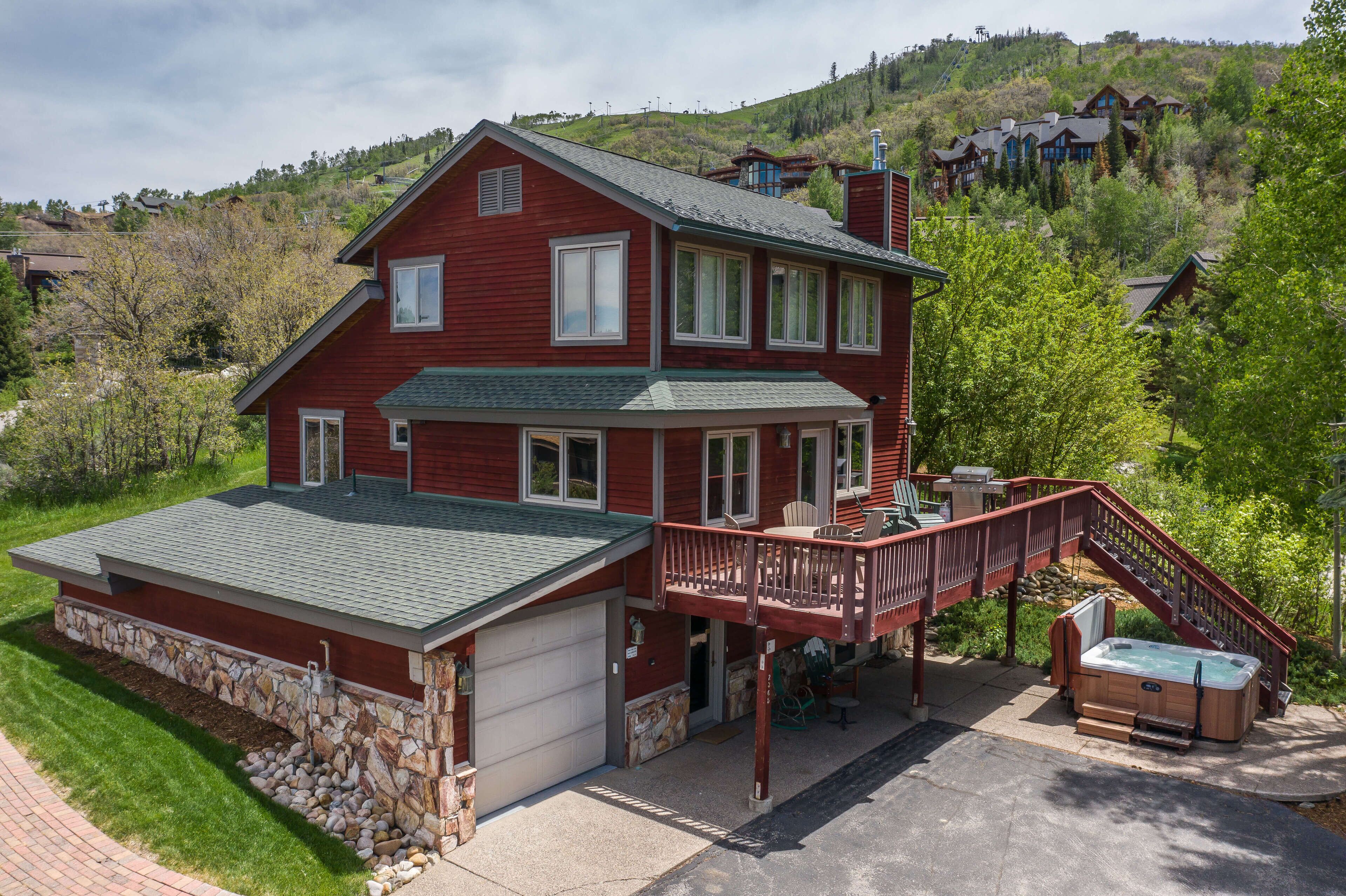 A two-story house with a stone foundation, a covered porch, and a hot tub.