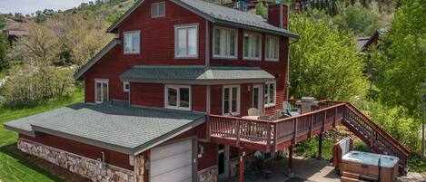 A two-story house with a stone foundation, a covered porch, and a hot tub.