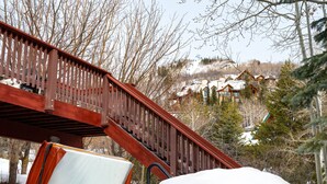 Una escalera de madera que lleva a un edificio con tejados cubiertos de nieve.