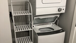 A compact laundry area with a front-loading washing machine and a metal drying rack. - A - Modern Cozy Room w Private Entrance & Washroom (Surrey)