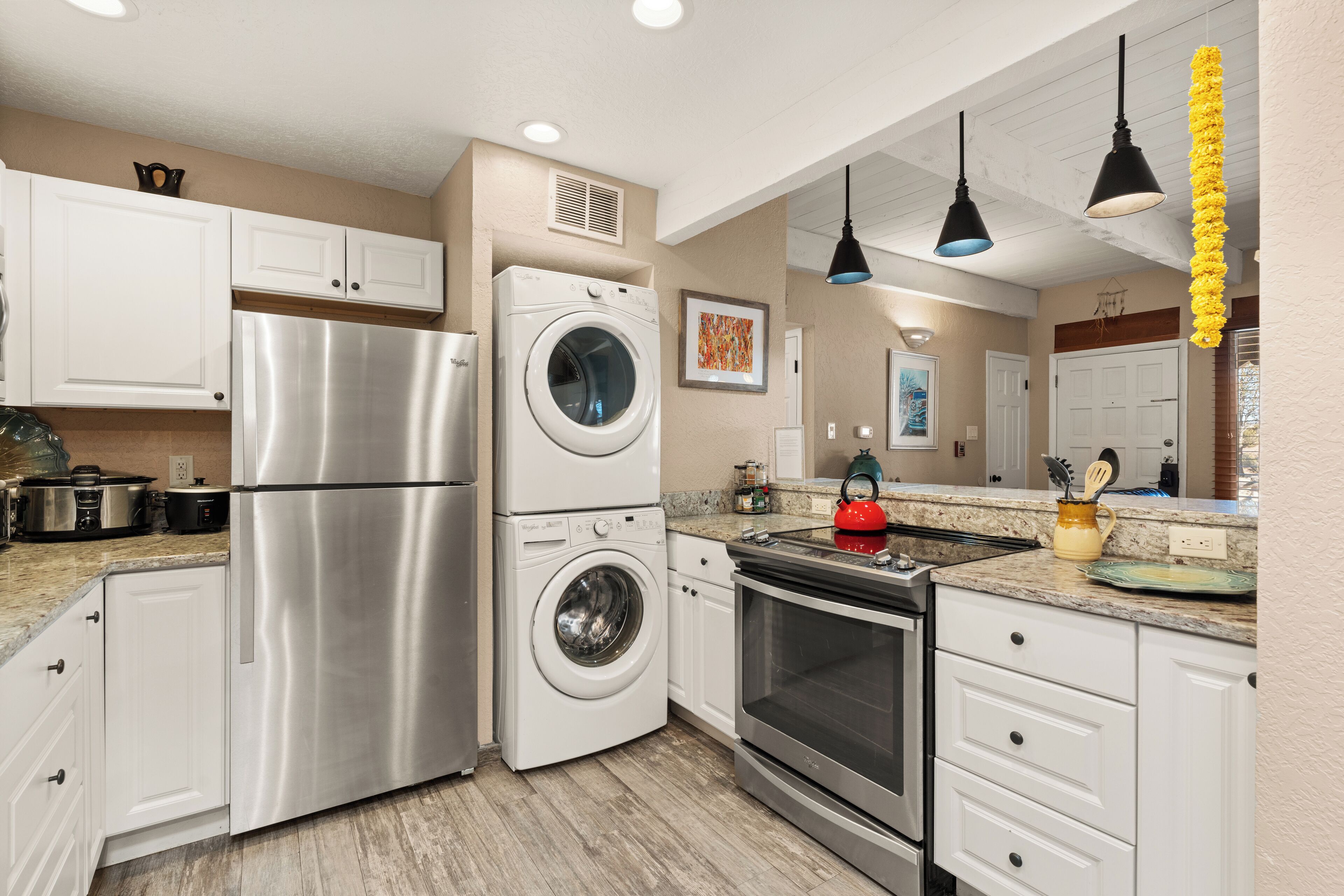 A modern kitchen with stainless steel appliances, white cabinetry, and pendant lighting.