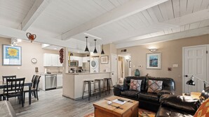 A spacious living area with a black leather sofa, a wooden coffee table, and a kitchen in the background. - Fort Marcy 32 | Walk to Plaza | Fireplace | Kitchen | Hot Tub | Pool | End Unit | Single Level (Santa Fe)