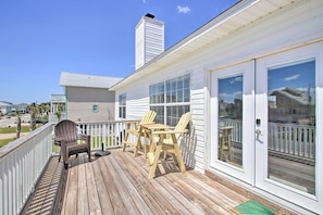 Relax on the deck with Adirondack chairs and a small table, surrounded by a residential setting.