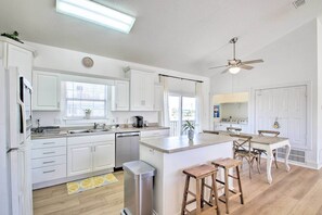 Enjoy cooking in this well-equipped kitchen with a central island, stools, and a window with blinds.