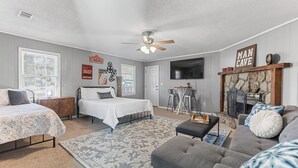 Quarto com cama, sofá, televisão e lareira.