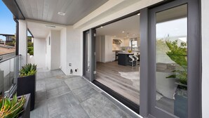 Ein modernes Wohnzimmer mit Küche, Essbereich und einem Balkon mit Topfpflanzen.