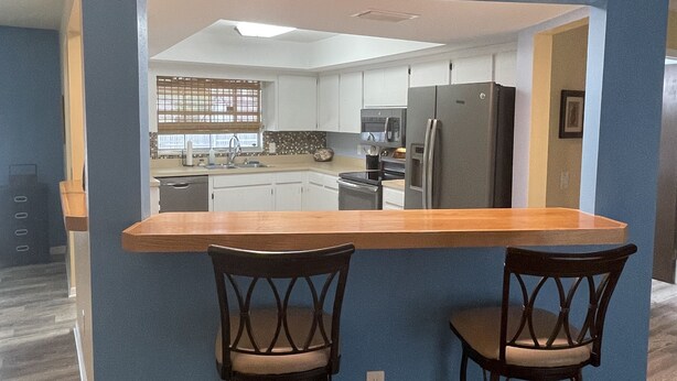 A modern kitchen with white cabinets, a central island, and stainless steel appliances.