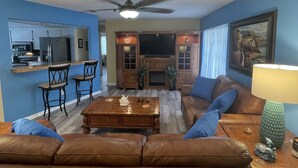 A living room with a brown leather sofa, a wooden coffee table, and a television.