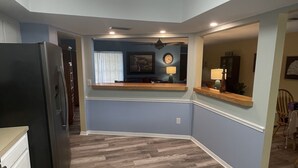 A kitchen with a refrigerator, a dining area with a table and chairs, and a ceiling fan.