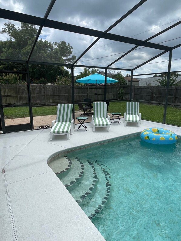 A covered outdoor swimming pool with lounge chairs and a blue inflatable ring.