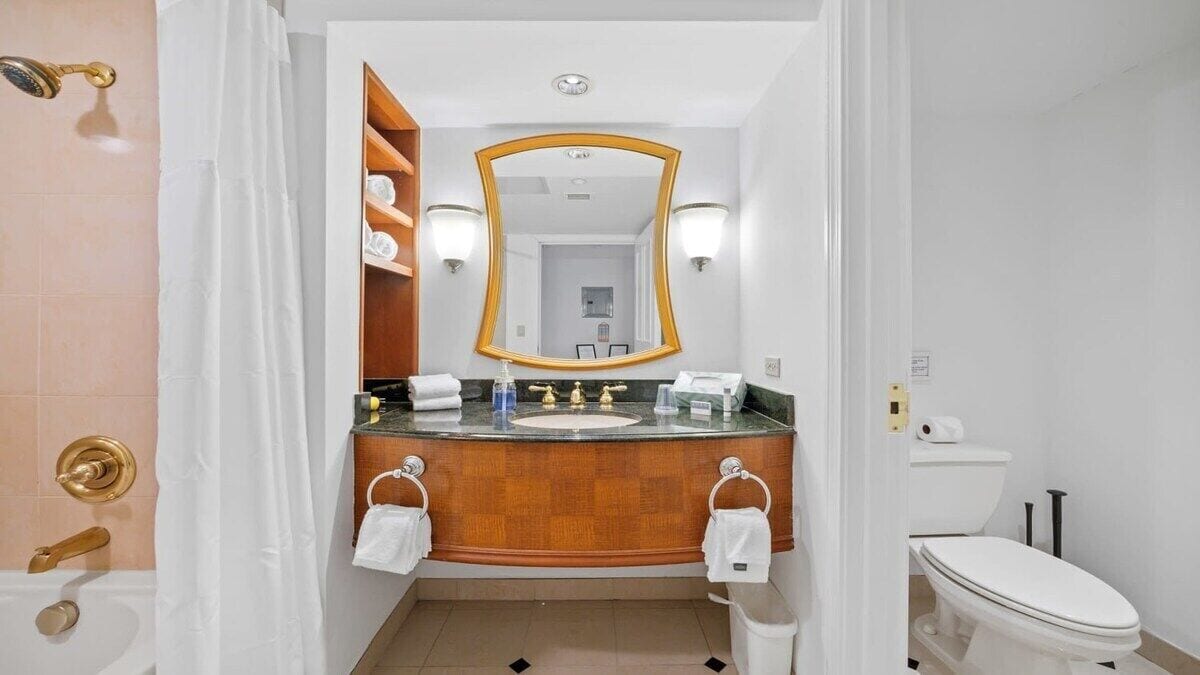 Un baño con tocador de madera, un espejo grande, inodoro y ducha.