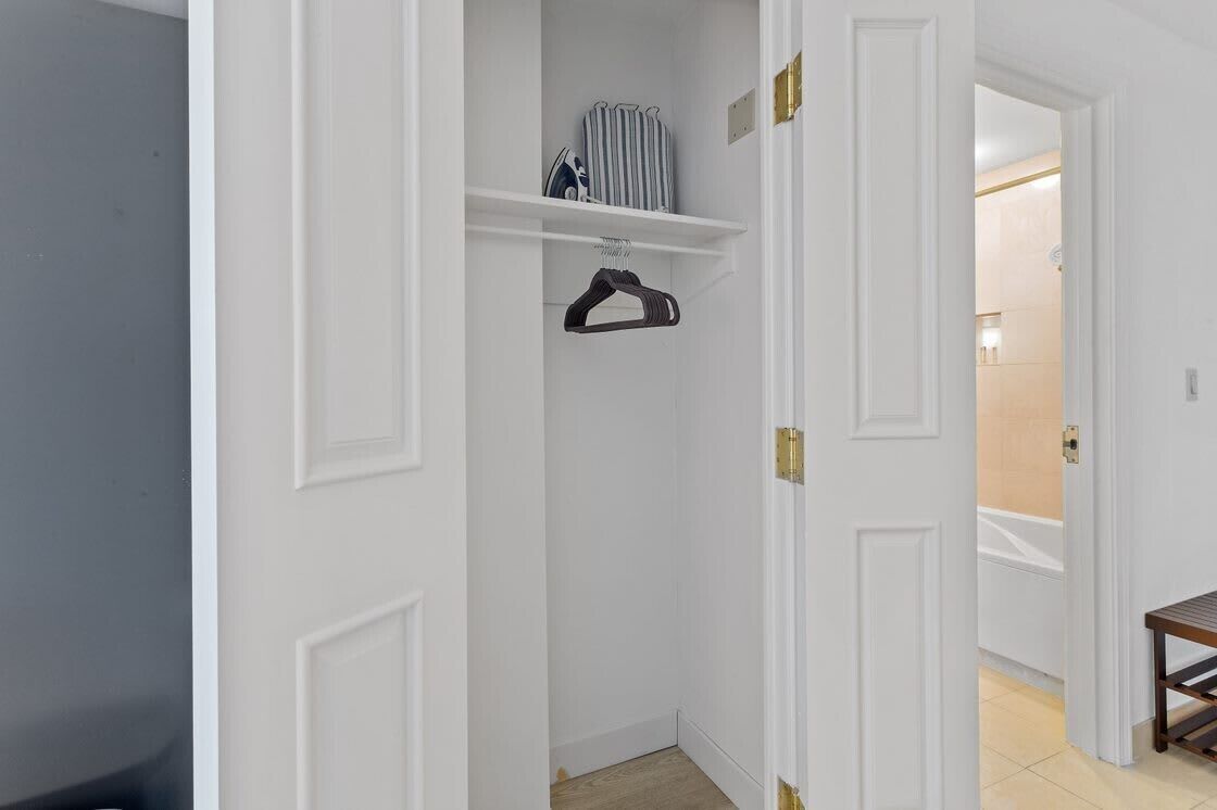 A hallway with a white door, a coat rack, and a small table.
