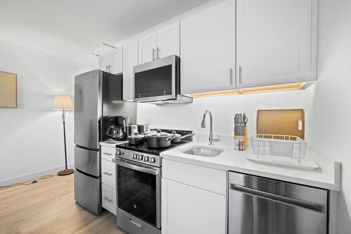 A modern kitchen with stainless steel appliances, white cabinetry, and a built-in microwave.